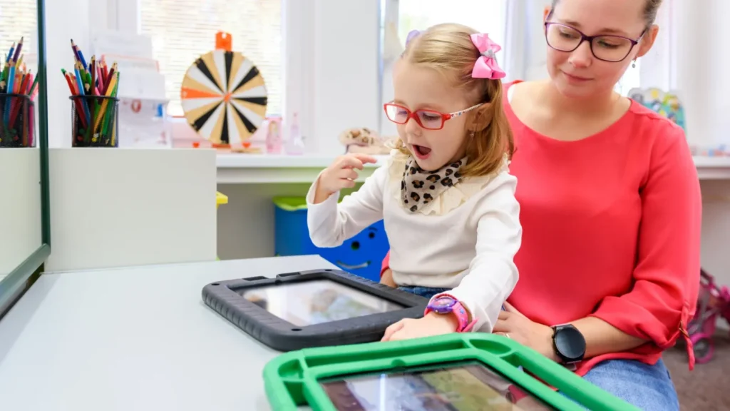 Therapist guiding a young girl through a tablet activity