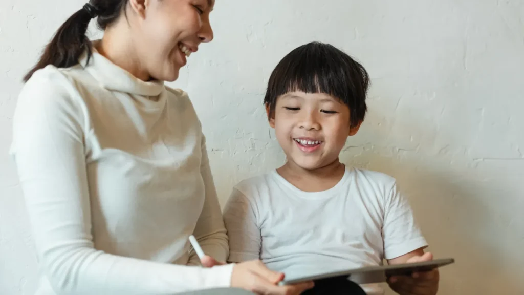 Mother and young son smiling while using a tablet together
