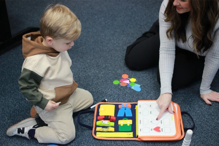 Therapist and child working on a busy board activity on the floor