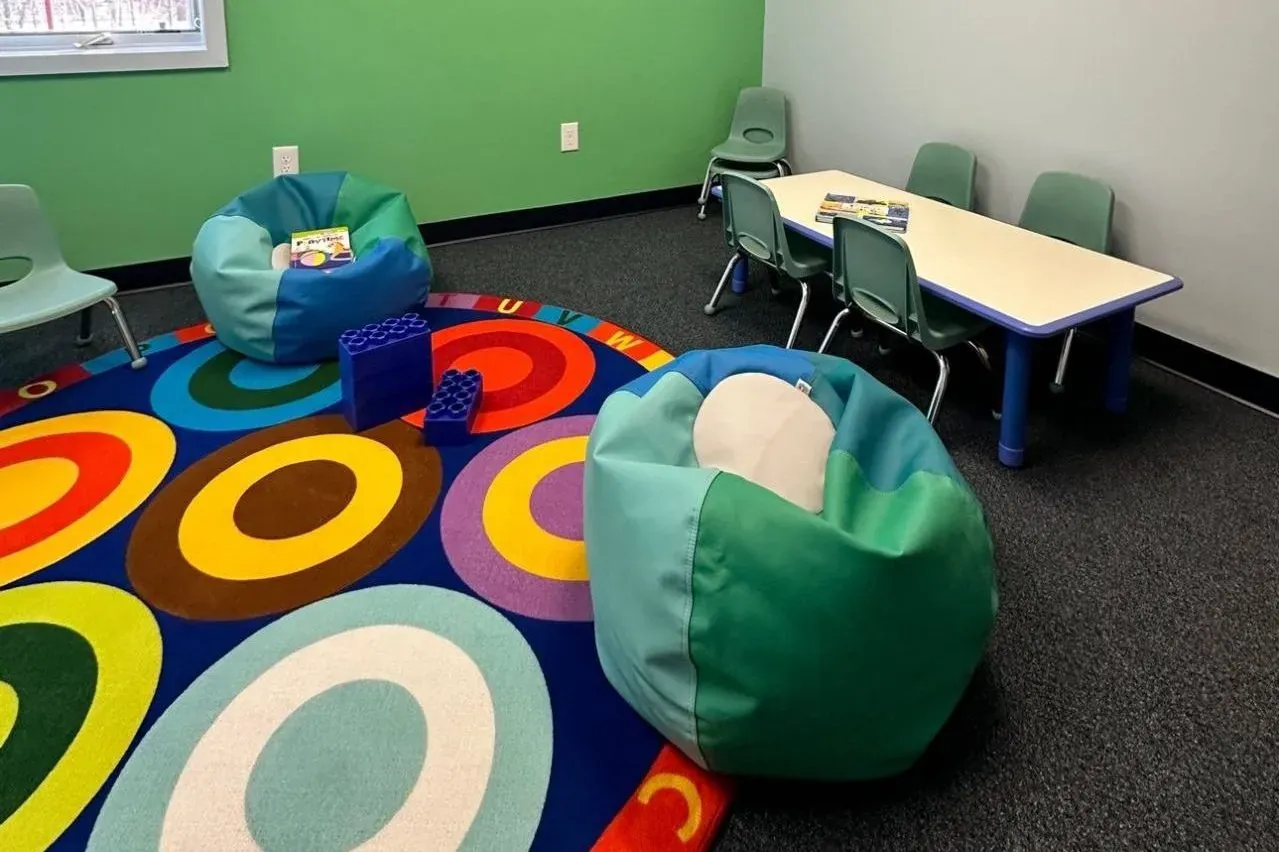 Classroom at the GentleCare Therapy autism center with colorful rug, tables and beanbags
