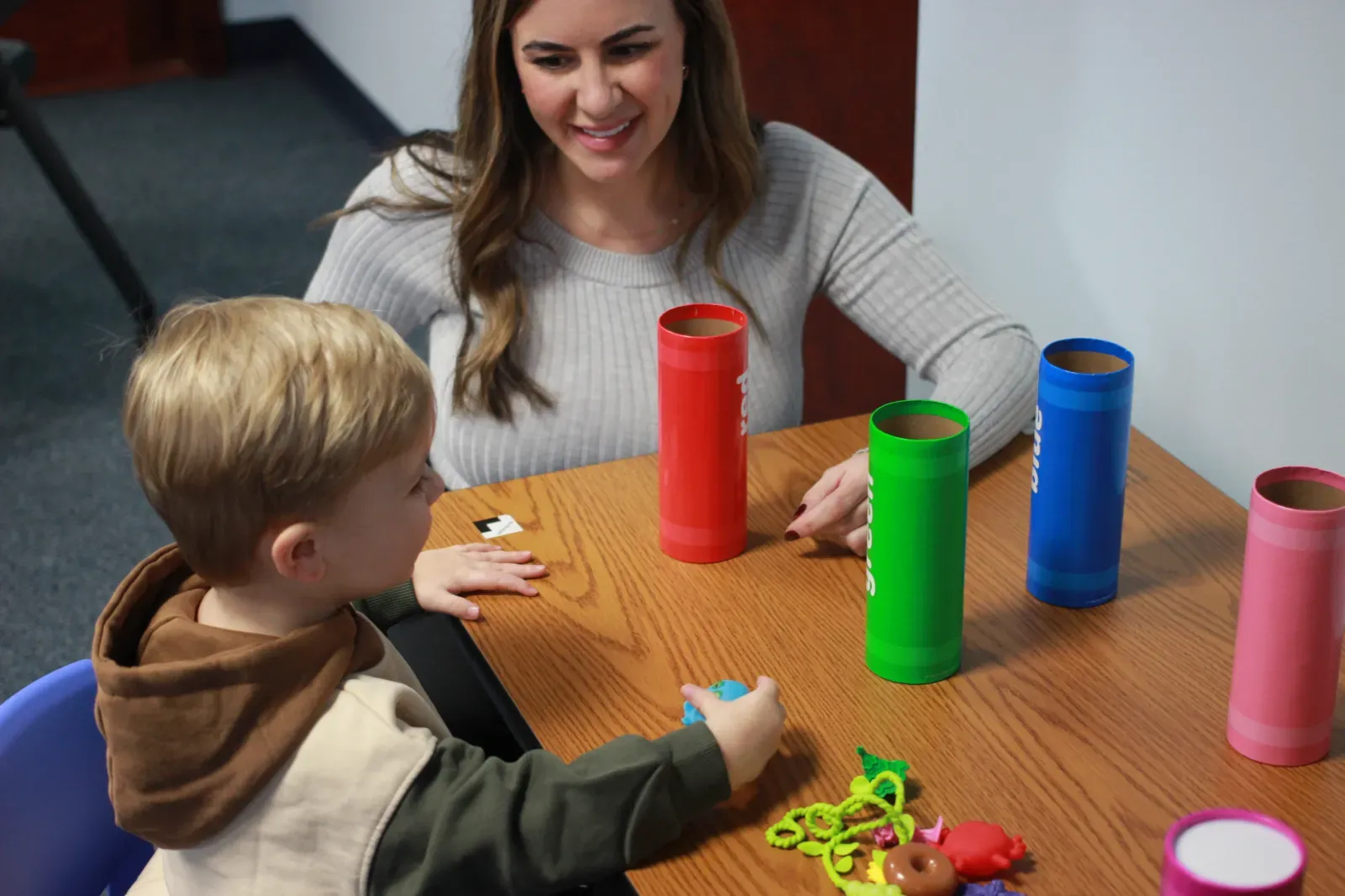 Child stacking colorful cups with a therapist in the full-day ABA program