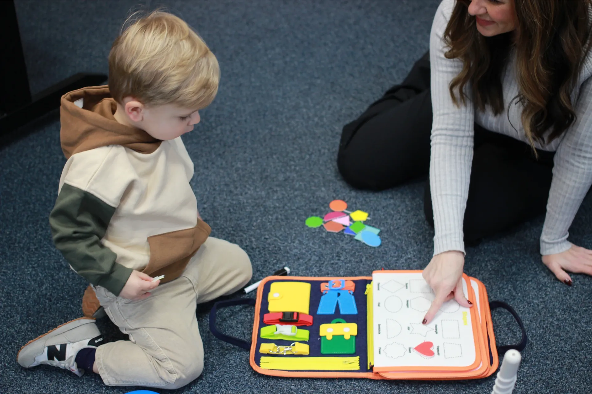 Therapist and child working on a busy board activity on the floor