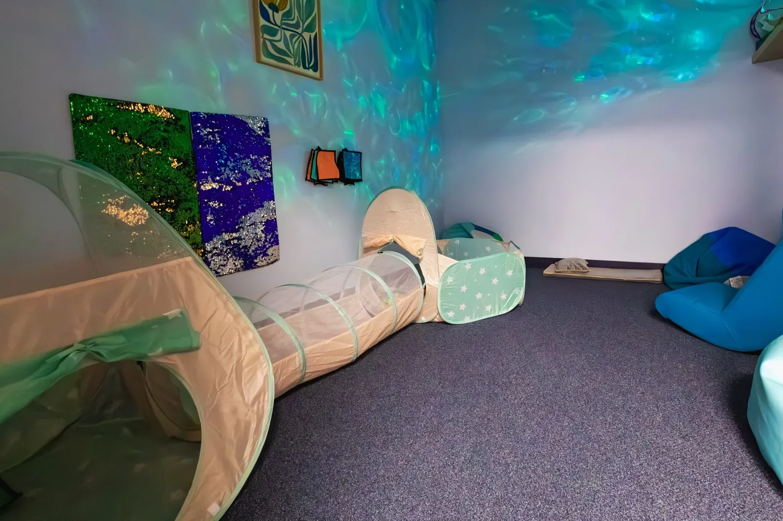 Calm-down room with a play tunnel, soft seating and projected lights