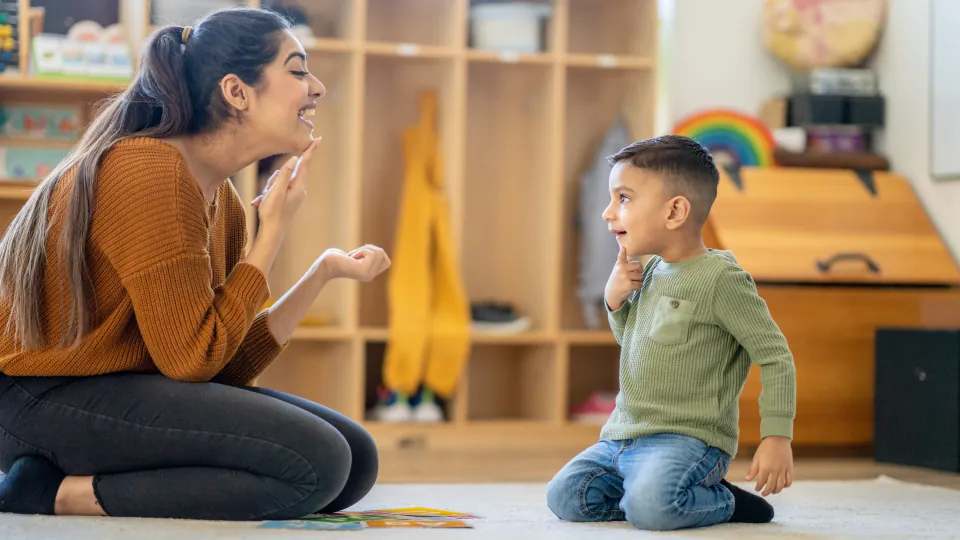 Therapist sitting on the floor with a young boy in a playroom