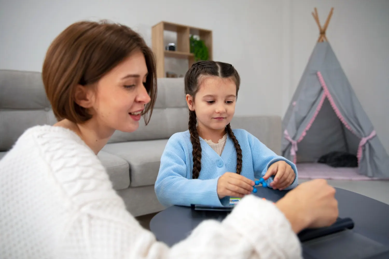 ABA therapist working one-on-one with a young girl at a table