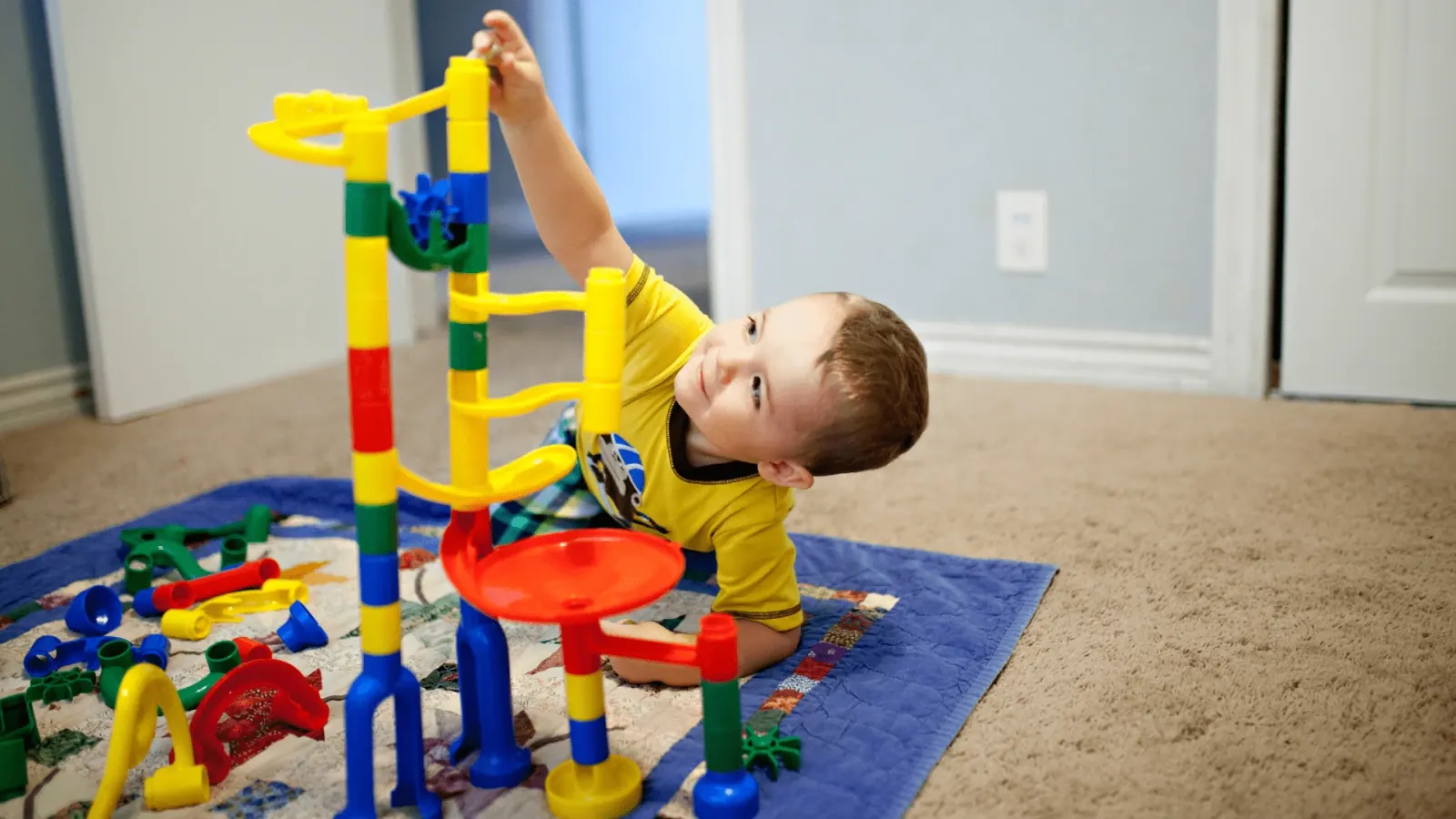 Child lying on the floor playing with building blocks at home