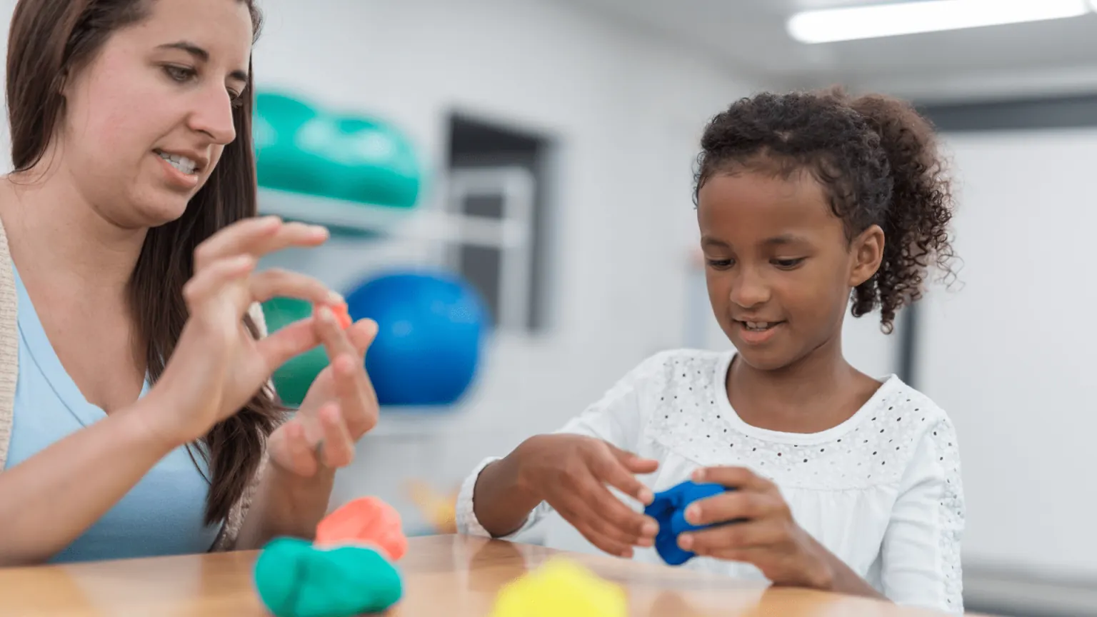 Therapist playing with a young girl using colorful toys