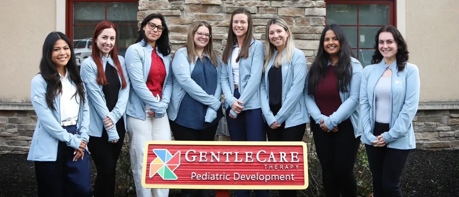 GentleCare Therapy team members standing behind the GentleCare sign
